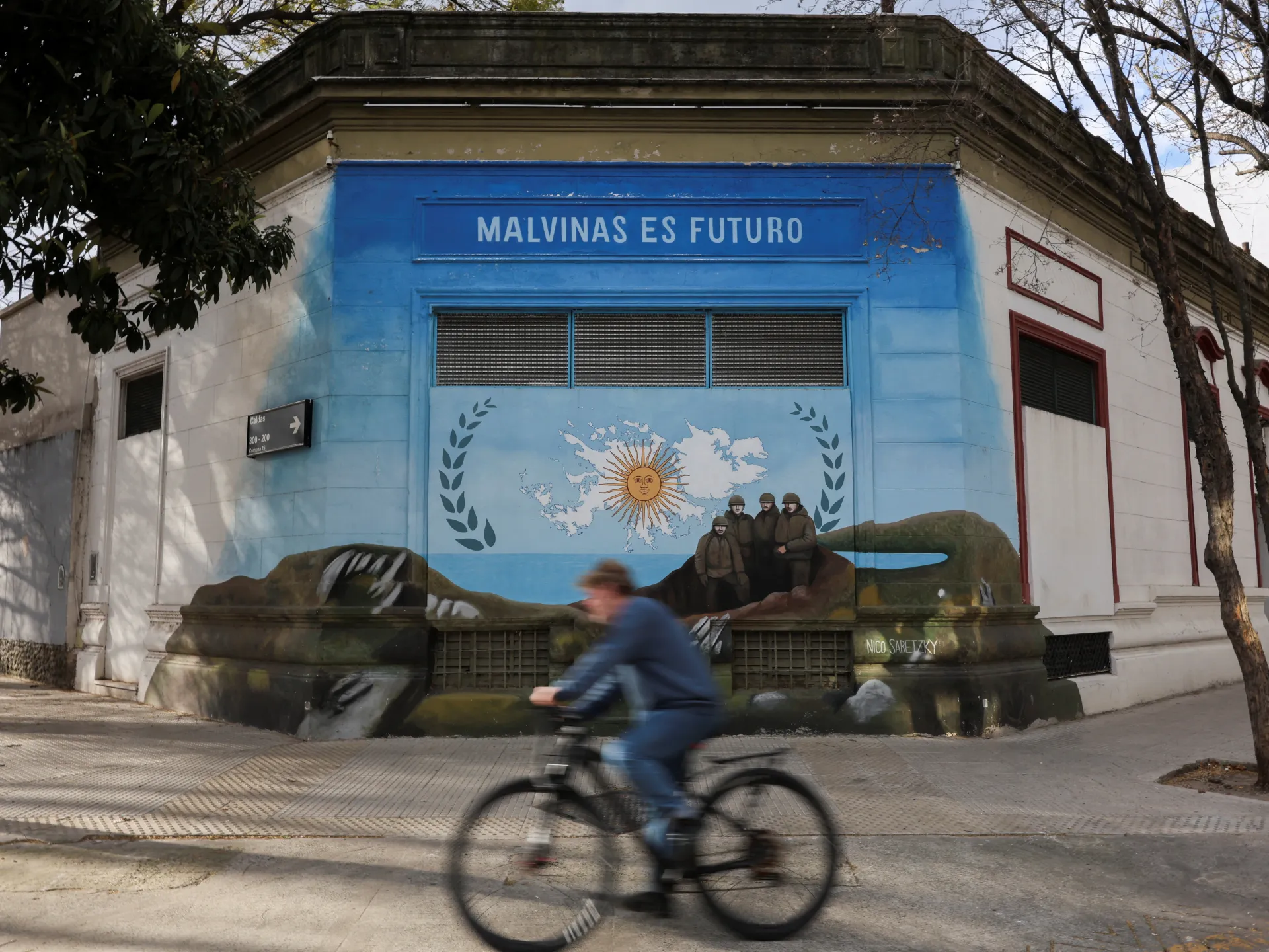 Blue mural depicting the Falkland Islands, Argentine imagery, and soldiers on an old building