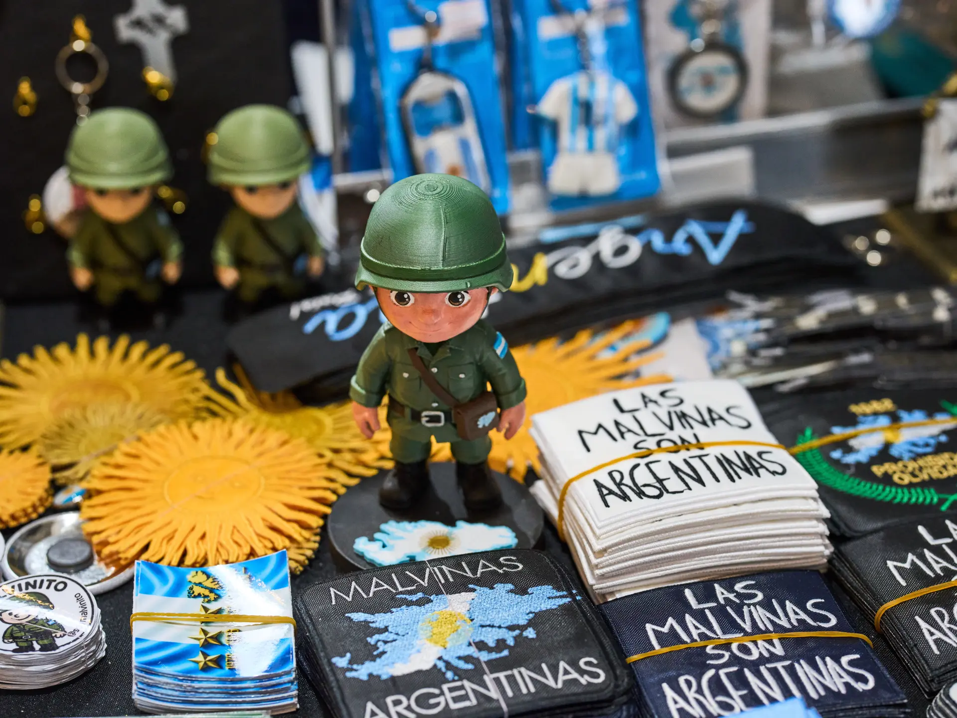 Toy soldier displayed among Malvinas-themed badges, patches, flags and printed memorabilia.