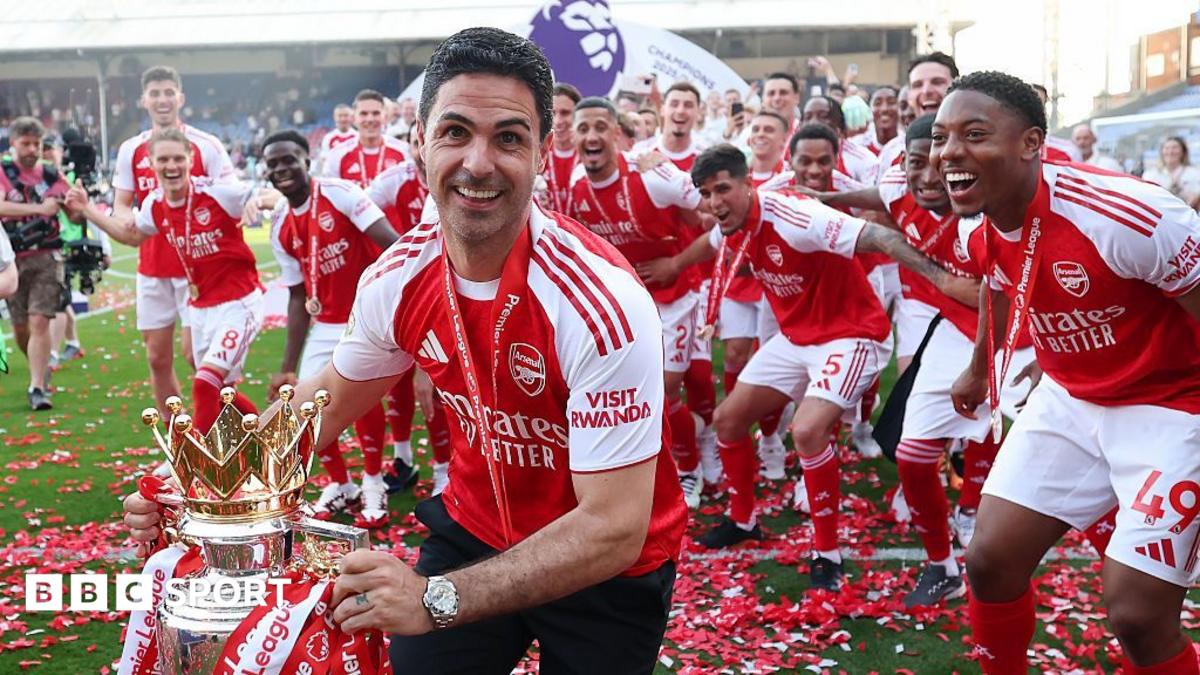 Arsenal players celebrate with a trophy as a man in team kit holds it foreground