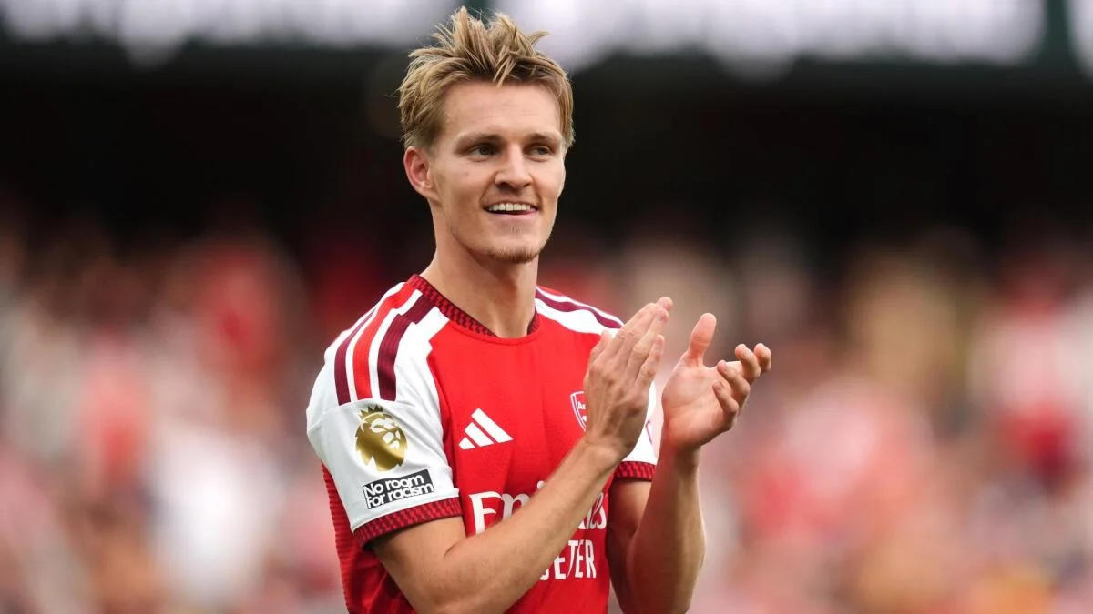 Arsenal footballer in red kit claps during a match at a stadium