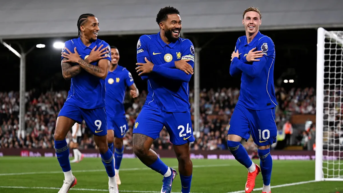 Three Chelsea footballers in blue kits celebrate with crossed arms during a match.