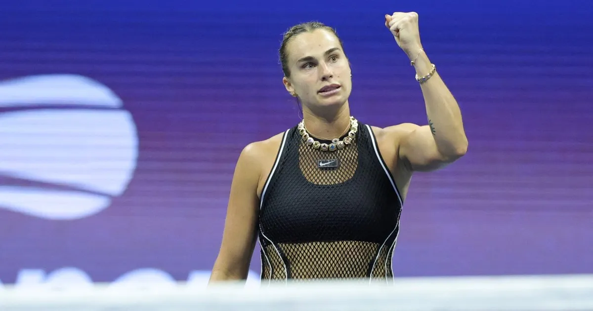 Tennis player in black outfit raises a clenched fist against a purple background