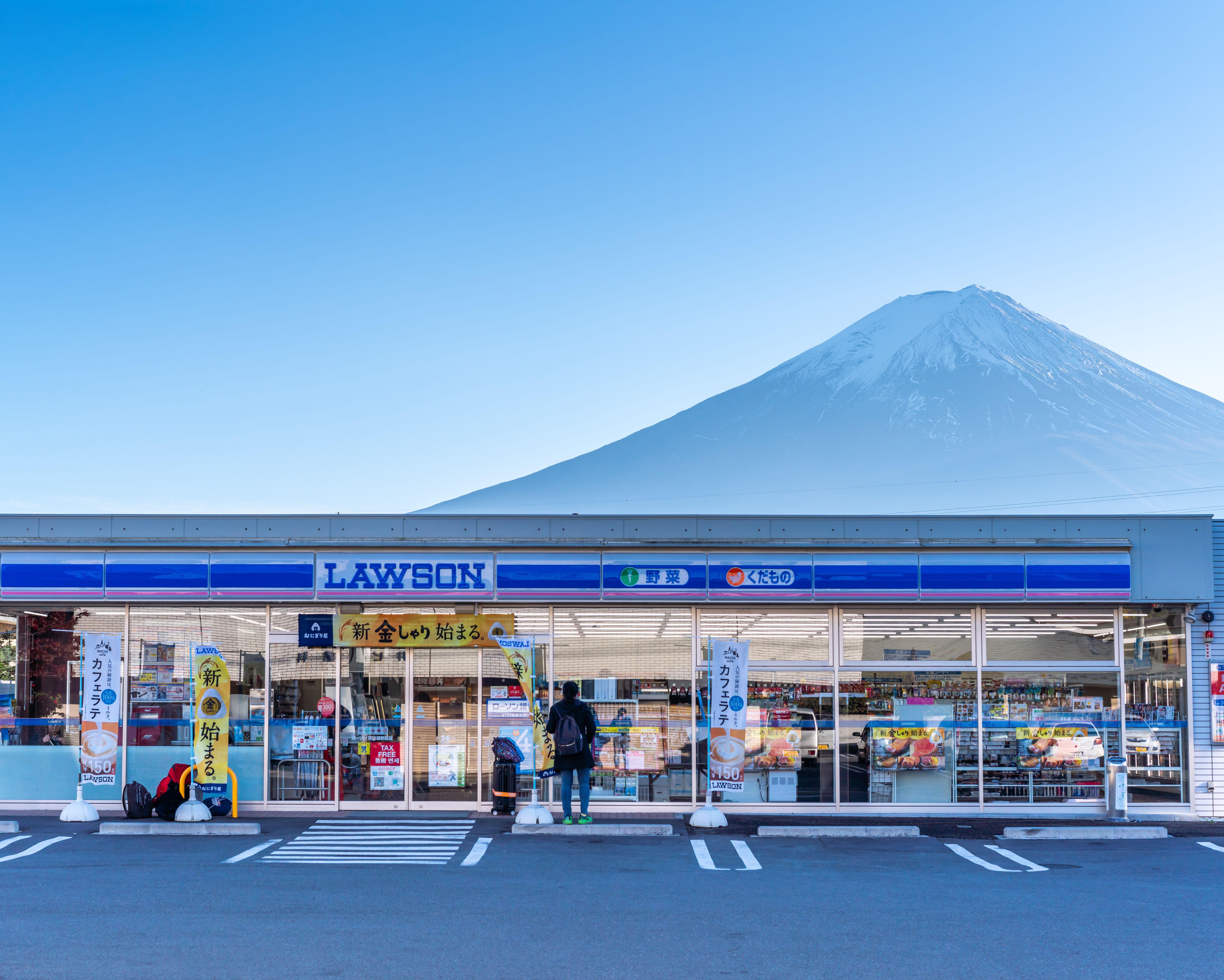 Lawson convenience store with snow-capped Mount Fuji rising behind it under a clear blue sky