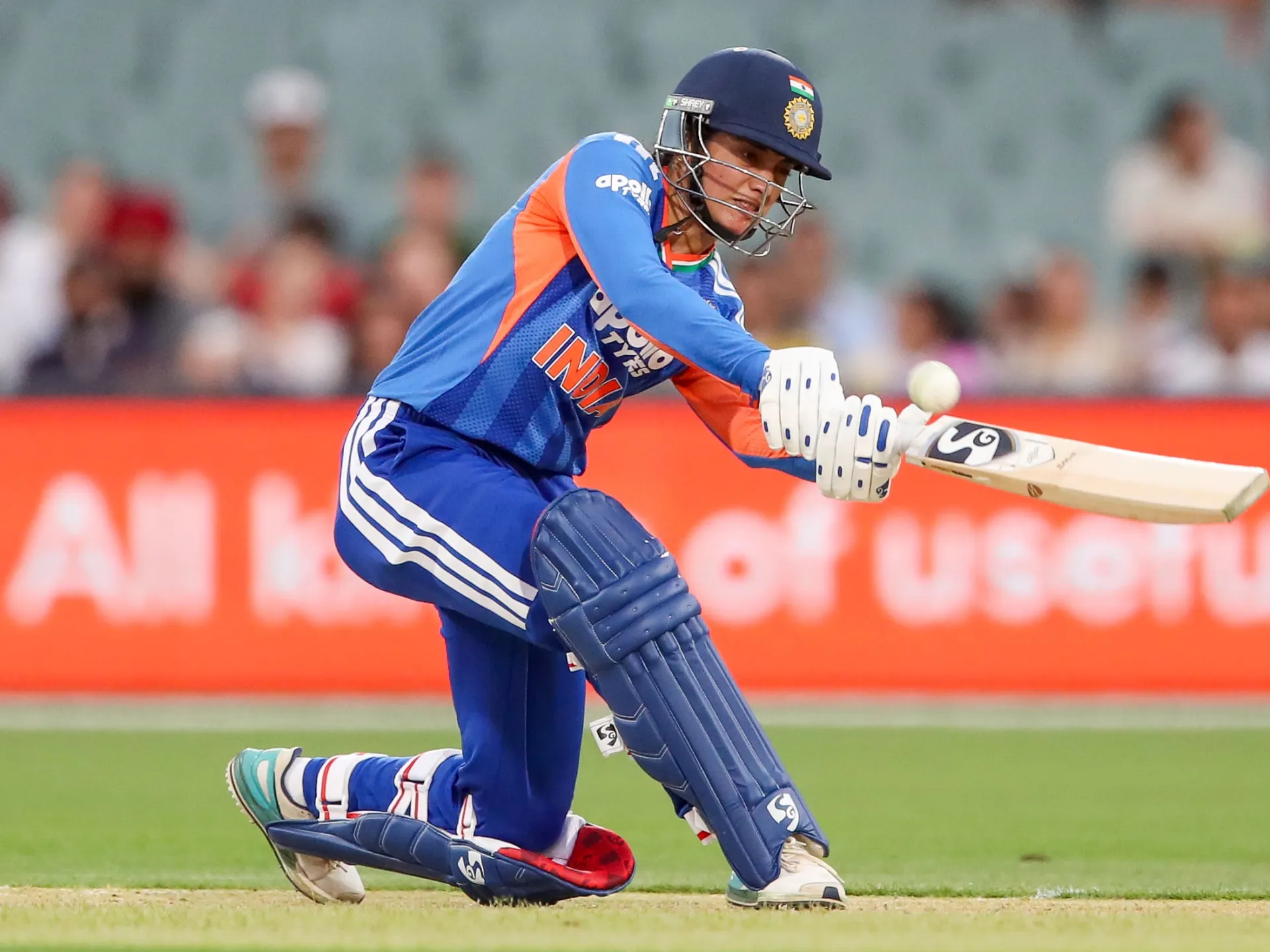 Indian women’s cricketer kneels while playing a sweeping shot during a T20 match
