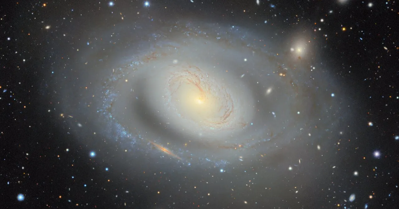 Bright spiral galaxy surrounded by stars and distant galaxies against a dark space background