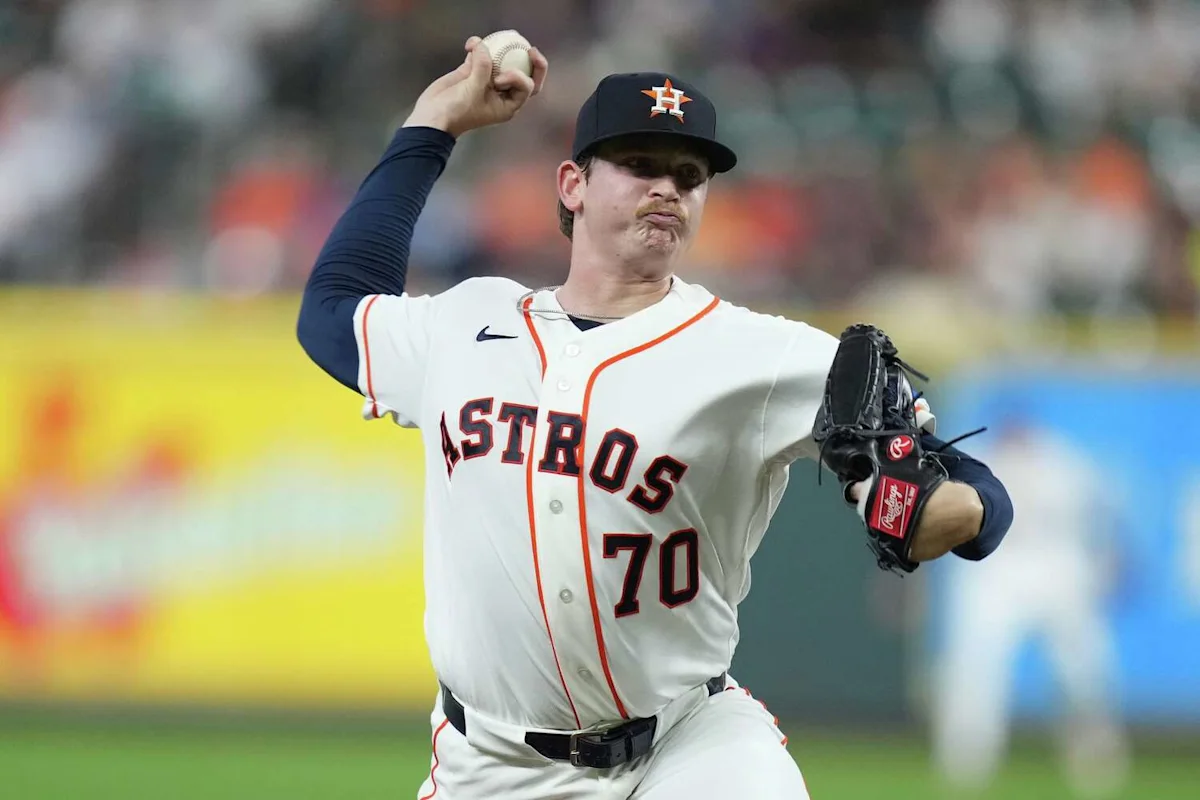 Astros pitcher in uniform winds up to throw during a baseball game