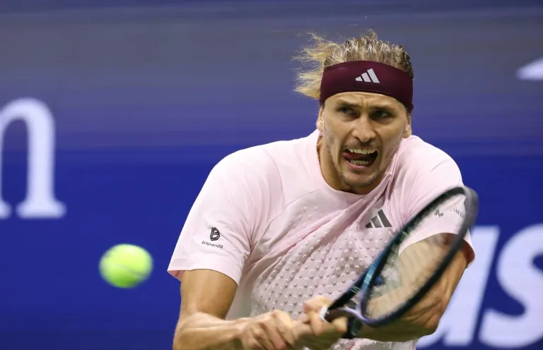 Tennis player in pink shirt and headband strikes a forehand during a match.
