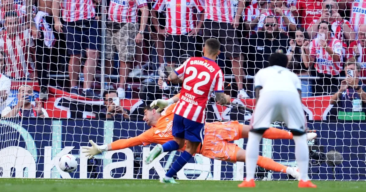Atlético Madrid player celebrates as Real Madrid goalkeeper dives toward the ball during a derby match