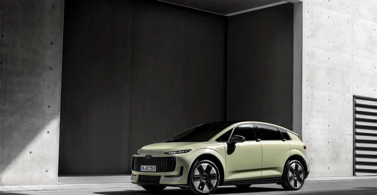 Light green Audi electric hatchback parked outside a modern concrete building