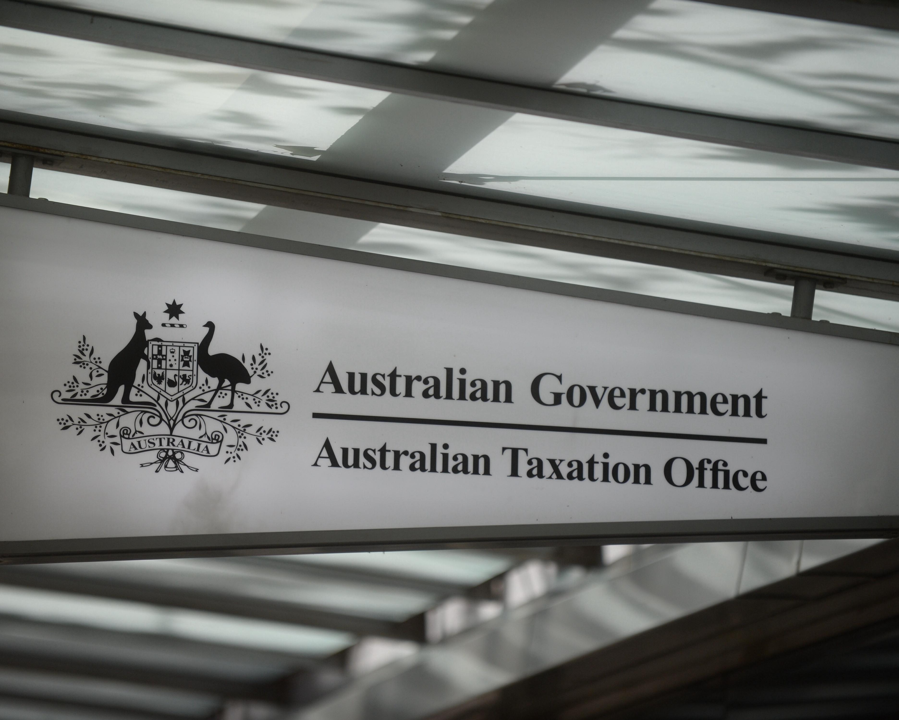Sign for the Australian Taxation Office beneath a glass roof, photographed at an angle.