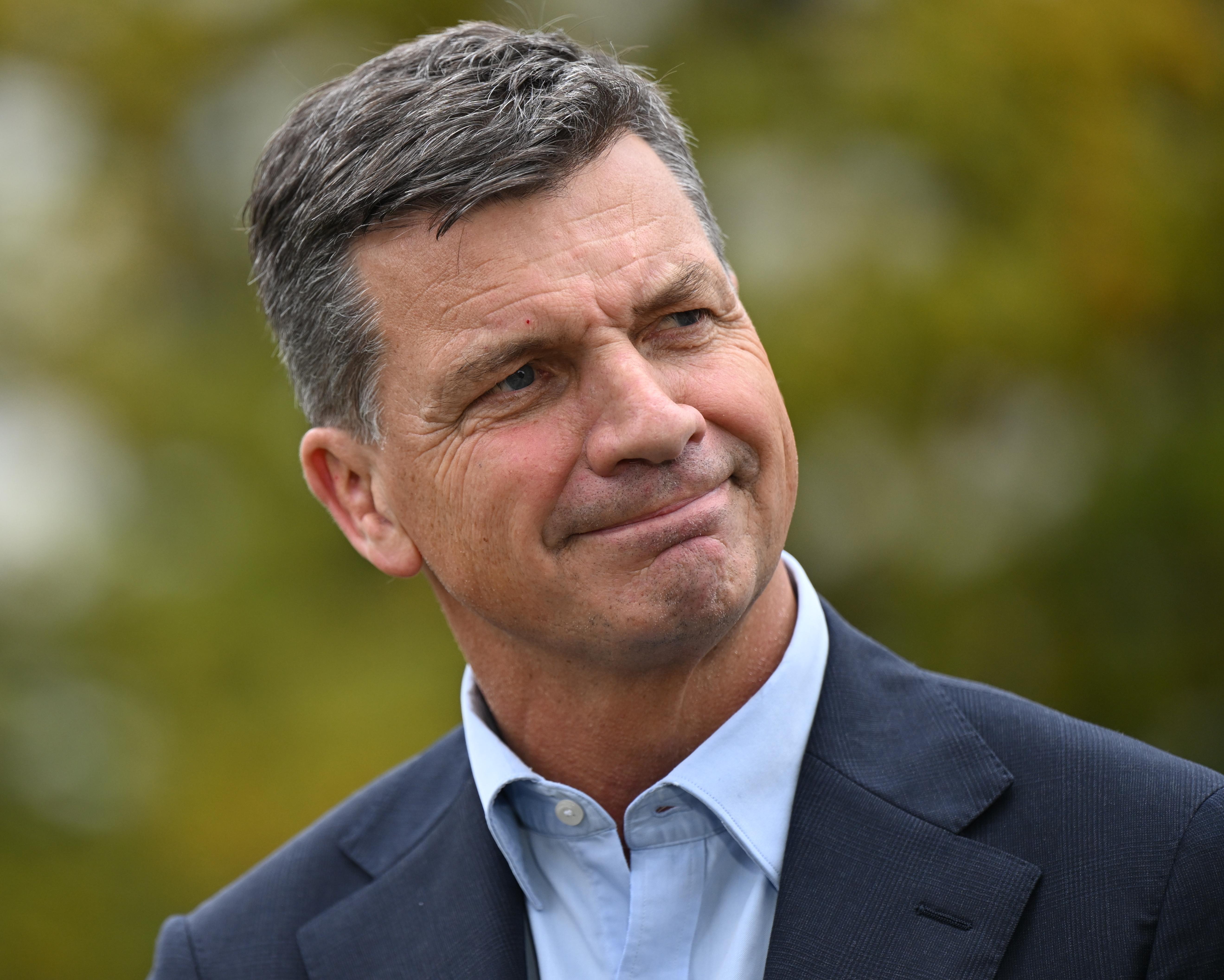 Close-up of a grey-haired man in a dark suit looking outdoors