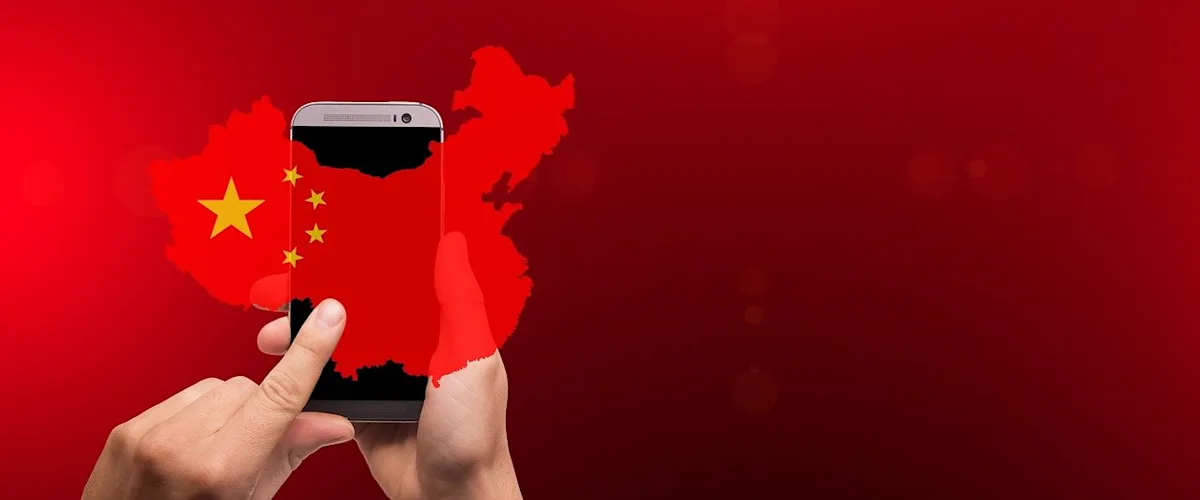 Hands holding a smartphone over a red map of China with Chinese flag stars