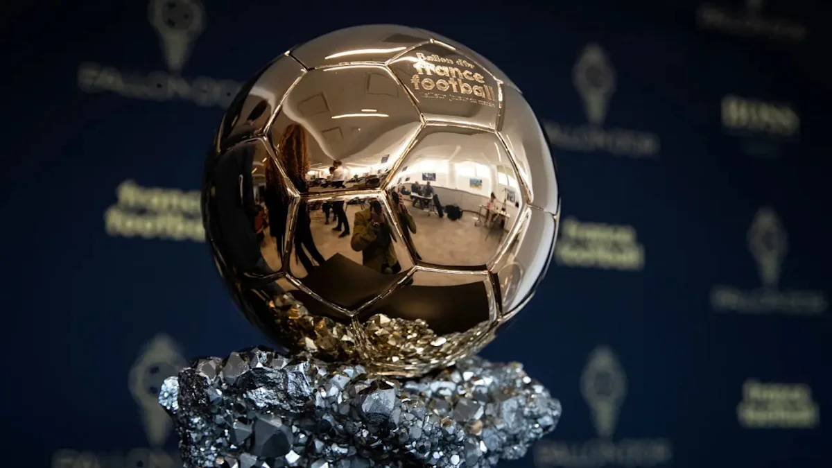 Reflective silver soccer ball trophy displayed on a faceted metallic base against a dark backdrop.