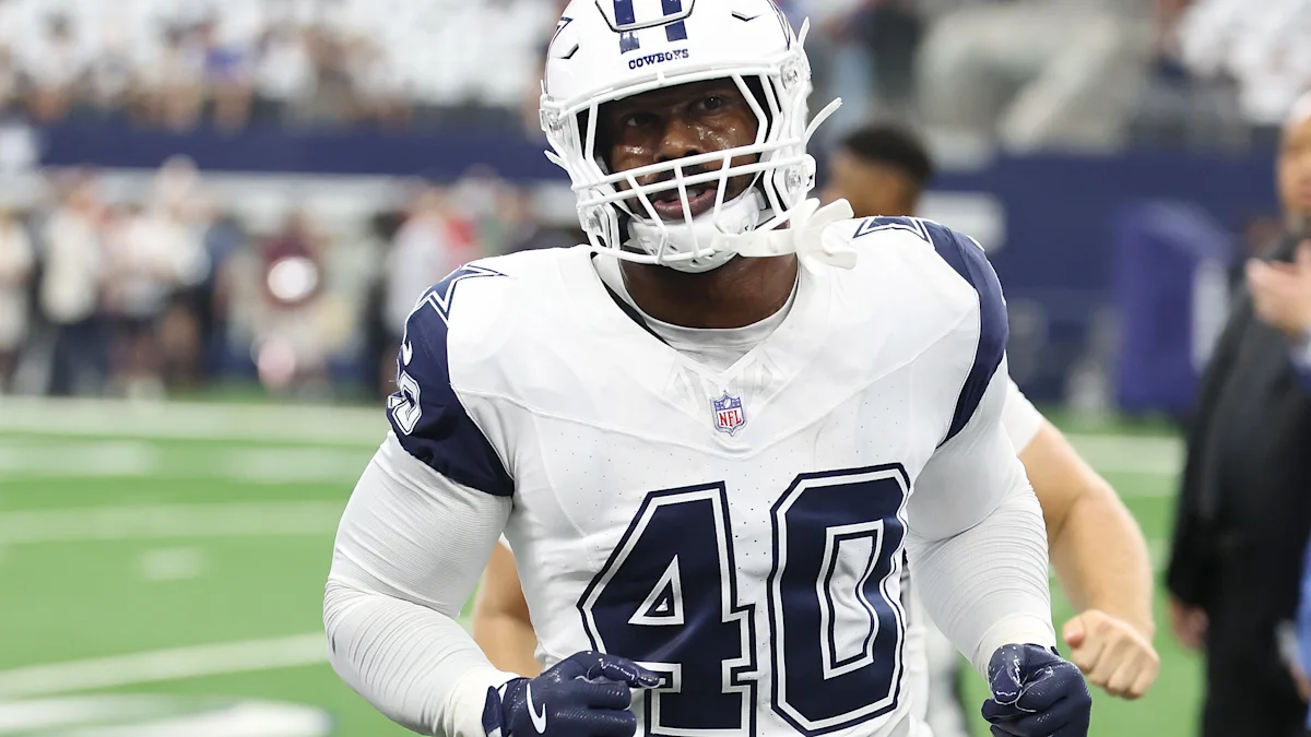 Dallas Cowboys player wearing a white number 40 jersey and helmet stands on the field.