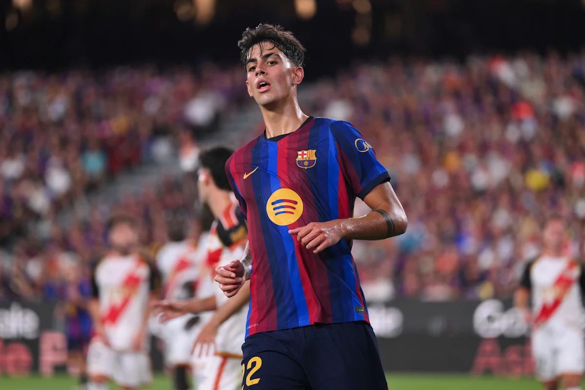 Barcelona footballer in striped jersey running during a match, with blurred players and crowd behind him.