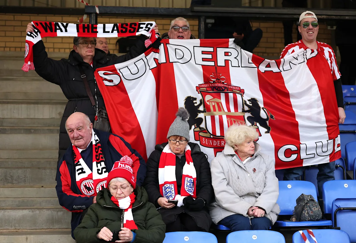 Sunderland supporters hold a large red-and-white club banner in stadium stands.