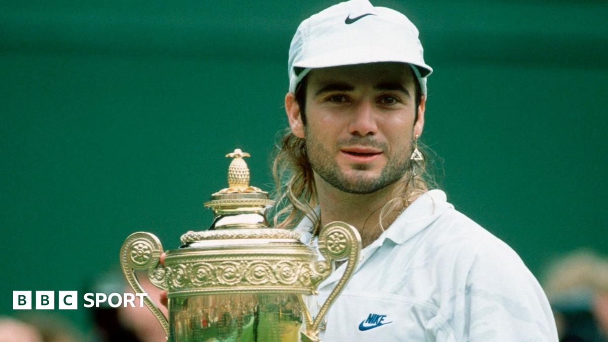 Man in a white cap and shirt stands behind an ornate trophy against a green backdrop.