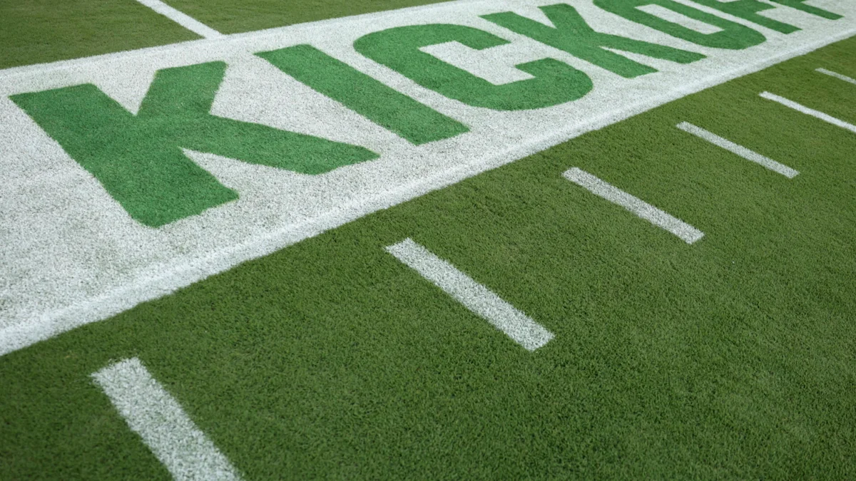 Close view of green football field turf with white boundary markings and large painted end zone letters.
