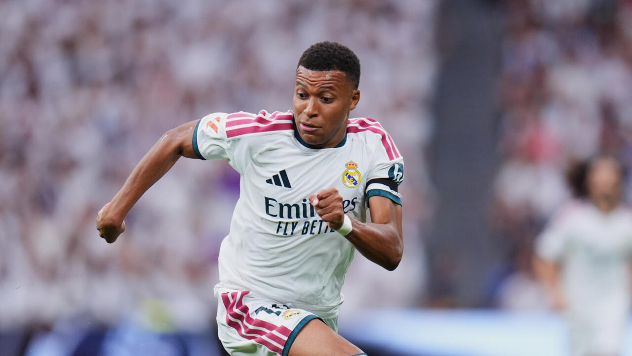 Footballer in a white Real Madrid jersey runs forward during a match.