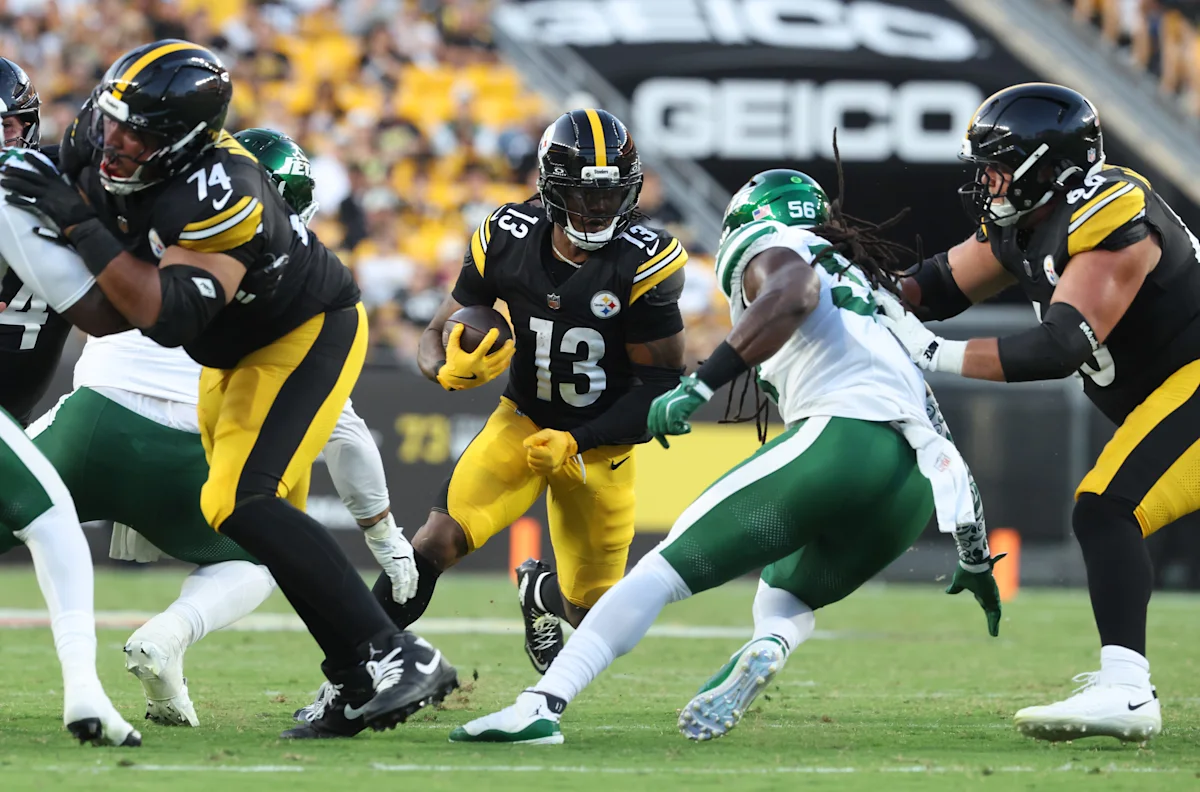 Steelers player in black and gold runs with the football as Jets defenders close in.