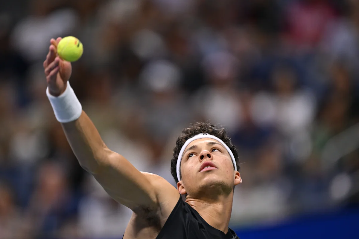Tennis player raises a ball and prepares to serve during a match.