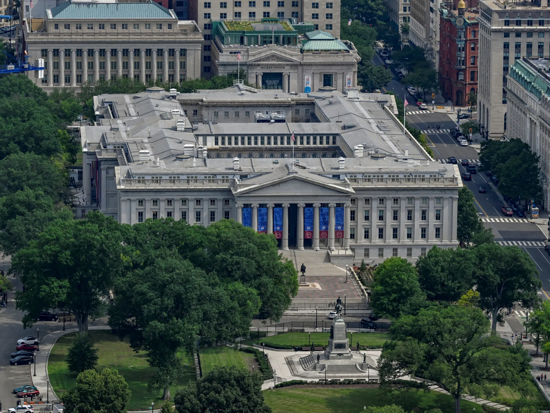 Aerial view of a grand neoclassical government building surrounded by trees, streets and city architecture.