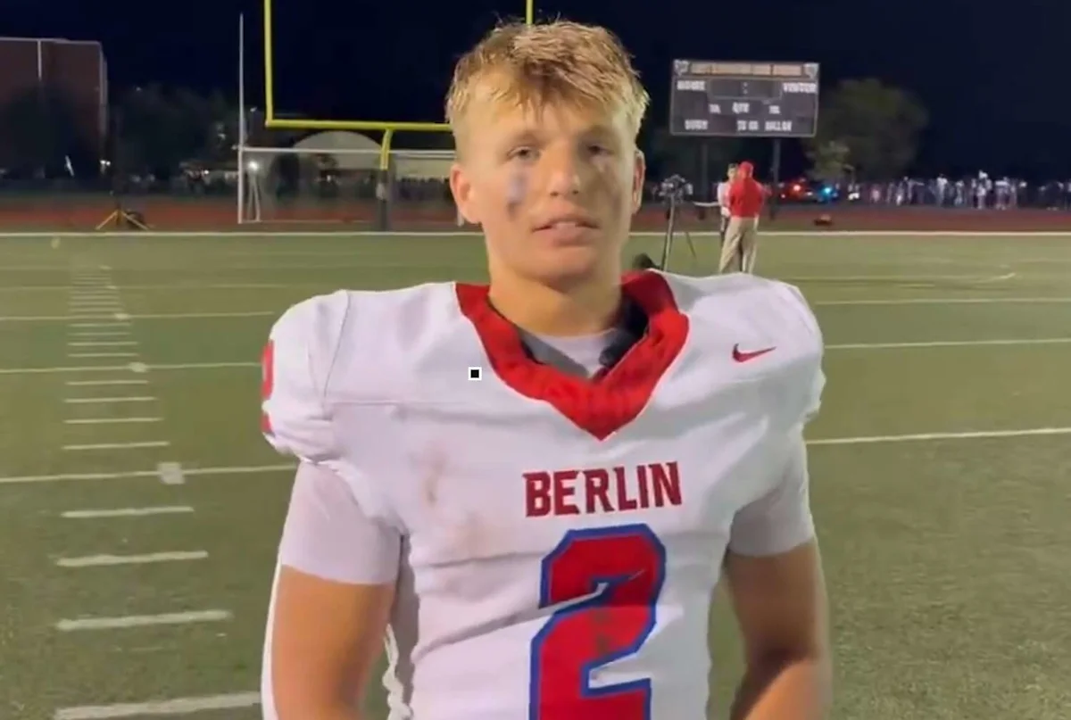 Football player in white Berlin jersey standing on field under stadium lights