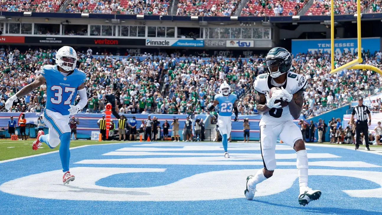 An Eagles player runs with the ball in the end zone as Titans defenders pursue during a football game.