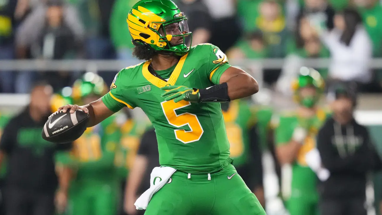 Oregon player in a green and yellow No. 5 uniform prepares to throw a football.