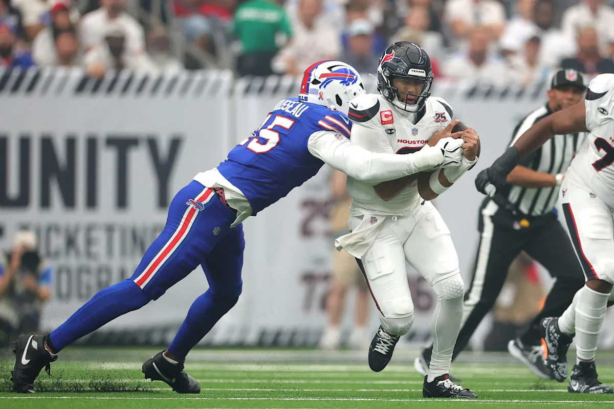 A Buffalo Bills defender reaches to tackle a Houston Texans quarterback during an NFL play.