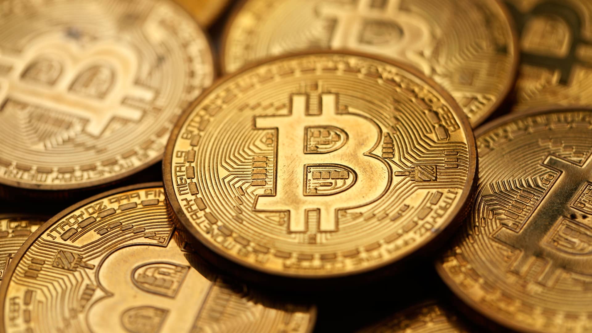 Close-up of overlapping gold-colored Bitcoin coins with the Bitcoin symbol prominently visible