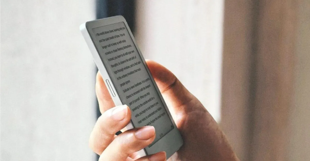 Hand holding a small e-reader displaying lines of text