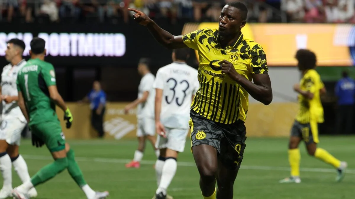Borussia Dortmund player in yellow and black kit points while running during a soccer match.