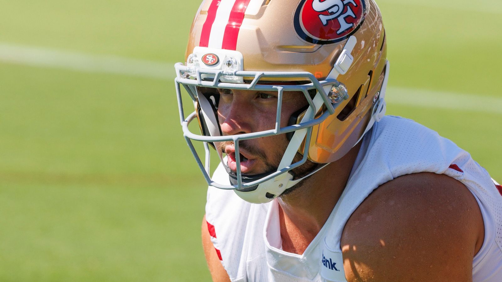 San Francisco 49ers player wearing a gold helmet and white jersey on the field
