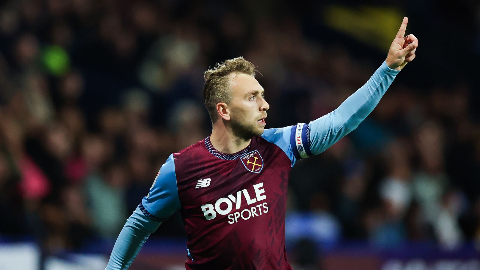 West Ham player in claret and blue raises one finger during a match