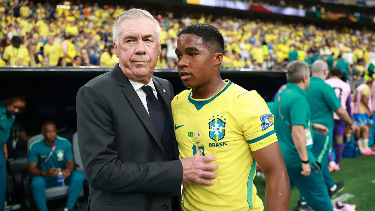 Brazil player in yellow jersey stands beside an older suited man at a crowded stadium