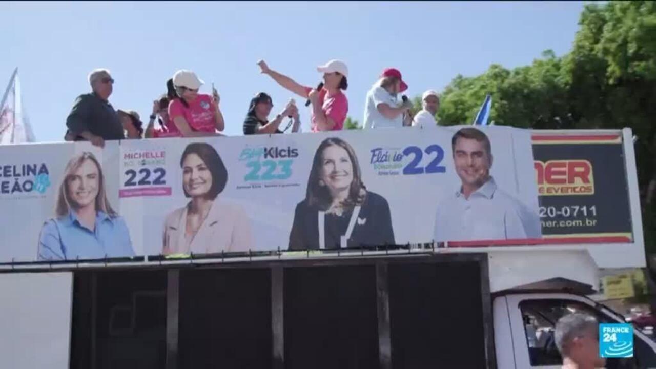 People stand atop a campaign truck displaying Brazilian political candidates' portraits and numbered election posters.