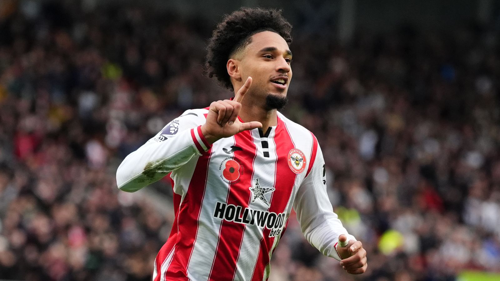 A Brentford player in a red and white striped shirt gestures during a match.