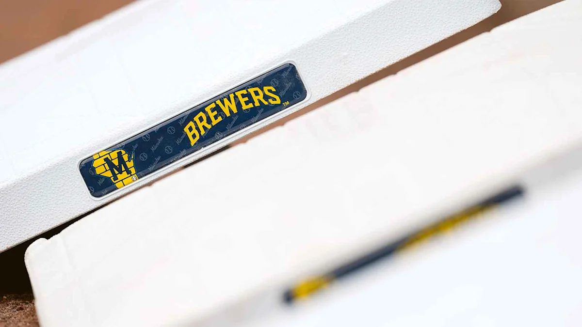 Close-up of a Milwaukee Brewers logo on white baseball equipment beside a blurred bat