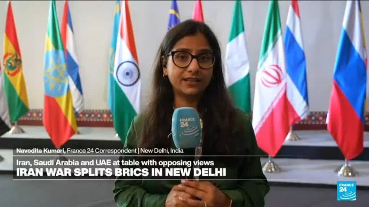 A female reporter speaks into a France 24 microphone before rows of national flags.