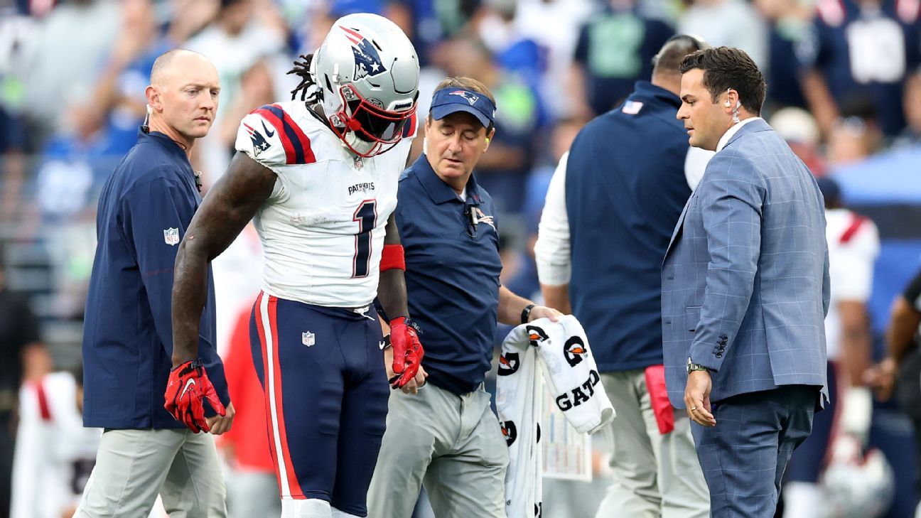 Patriots player in uniform is escorted from the field by team personnel.