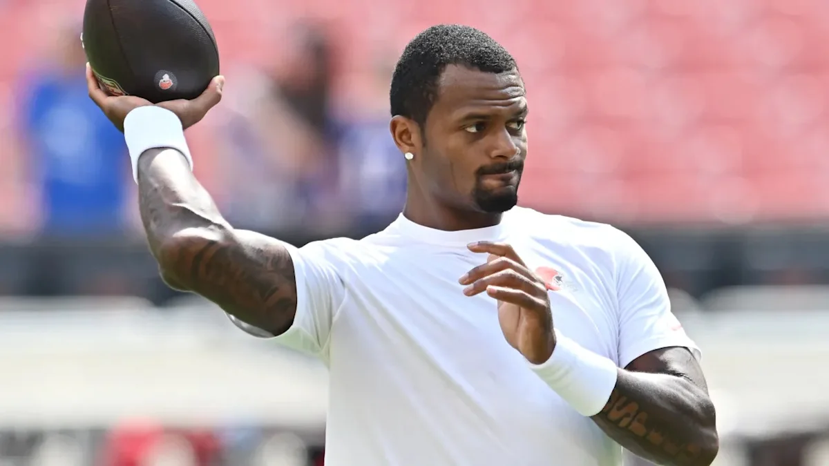 Football player in white shirt holding a ball during a practice throwing motion