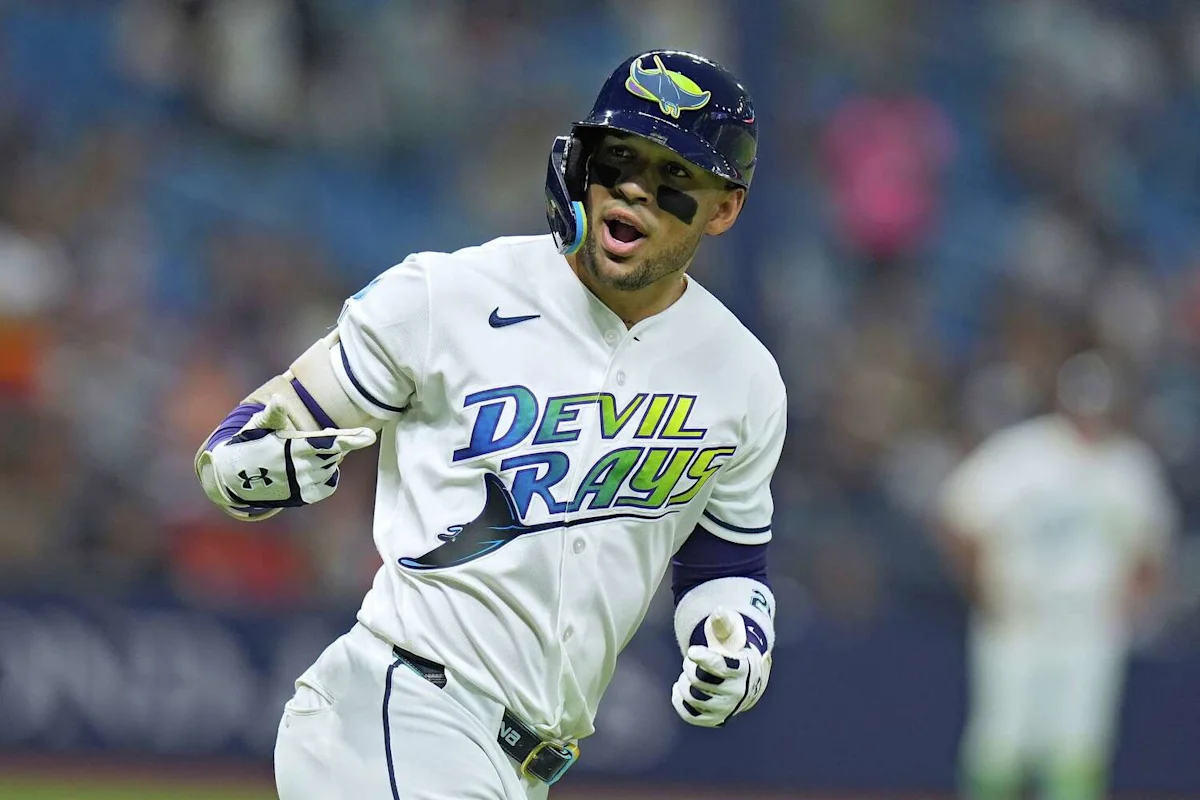 Baseball player in a Tampa Bay Devil Rays uniform runs while wearing a batting helmet and gloves.