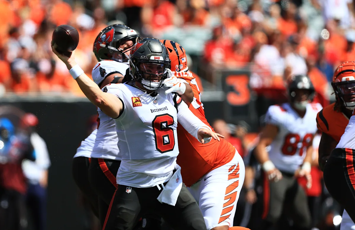 Buccaneers quarterback throws a football as Bengals defender reaches toward him during a game