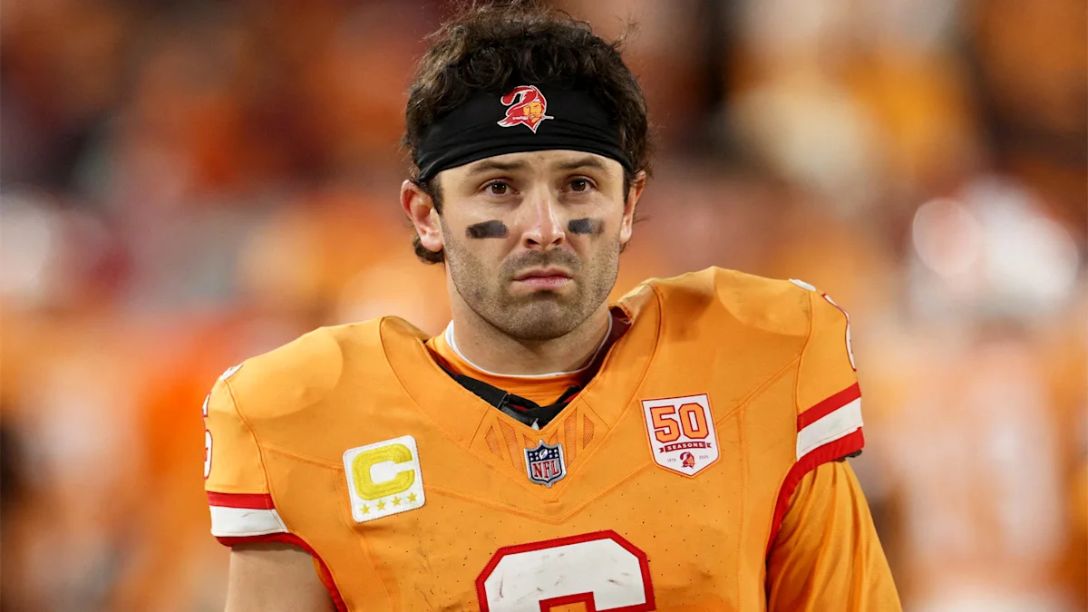 Football player in orange Buccaneers uniform and black headband standing on the field