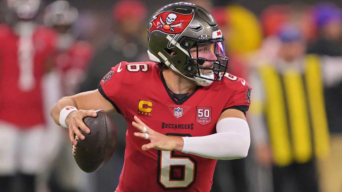 Buccaneers quarterback in red jersey and helmet prepares to throw a football.