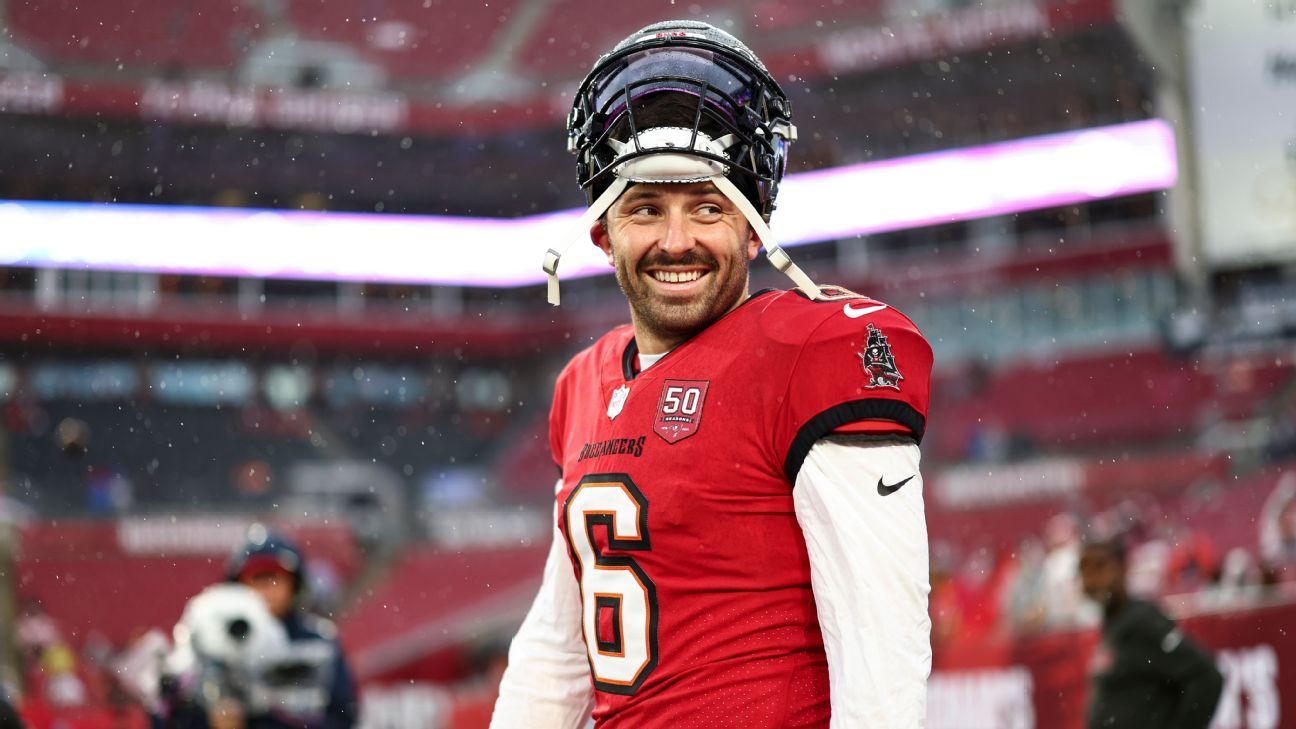 Tampa Bay Buccaneers quarterback in red jersey smiles beneath his helmet during snowfall.