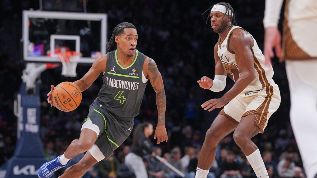 A Timberwolves player dribbles past a Suns defender during a basketball game.
