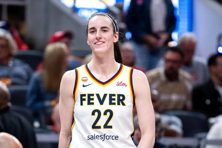 Basketball player wearing an Indiana Fever jersey smiles while standing on the court