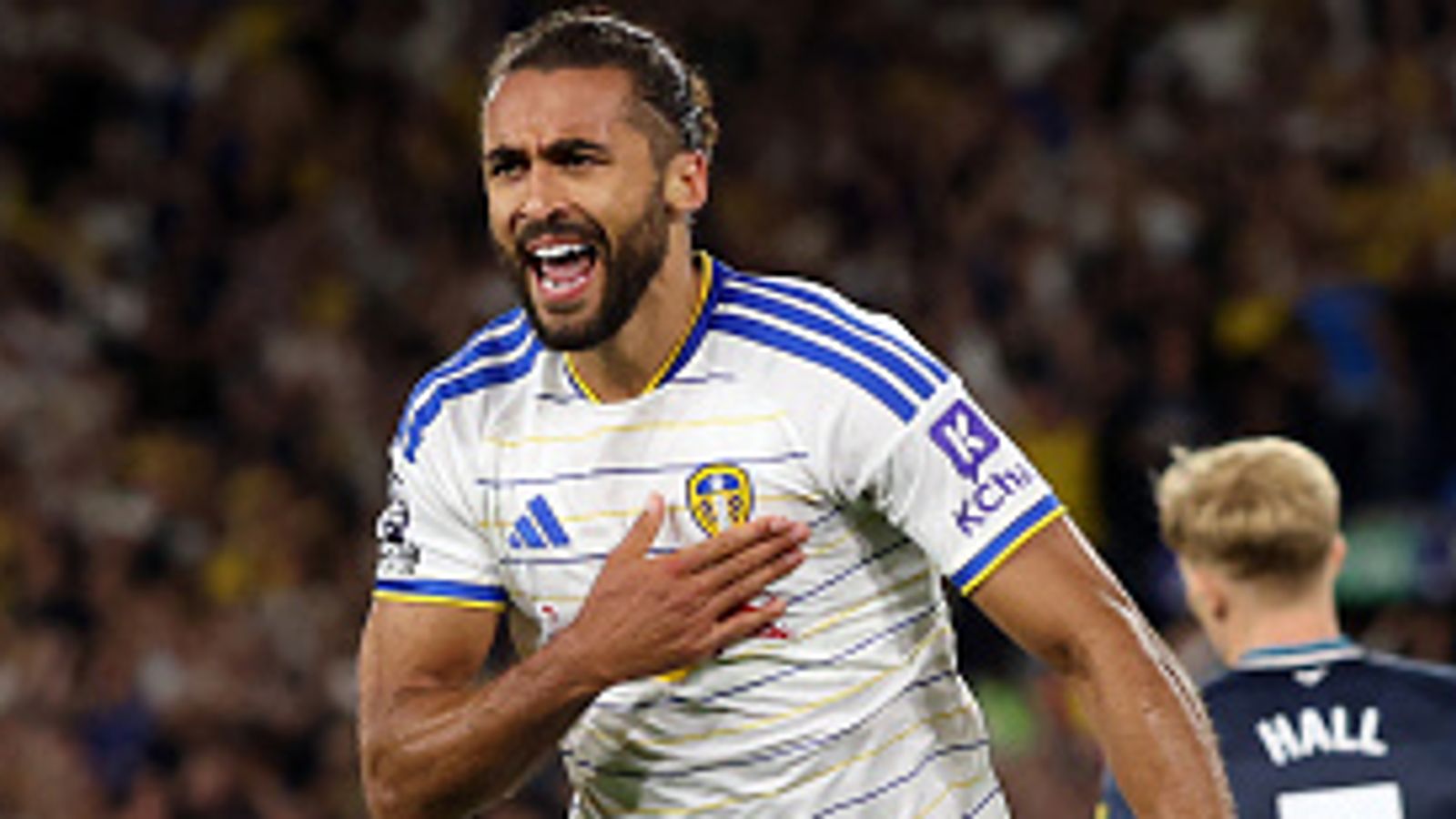 Leeds player celebrates with hand on chest during a match as an opposing player stands nearby